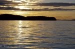 The lighting at sunset filters through the clouds over the peaceful waters off Northern Vancouver Island in British Columbia, Canada.